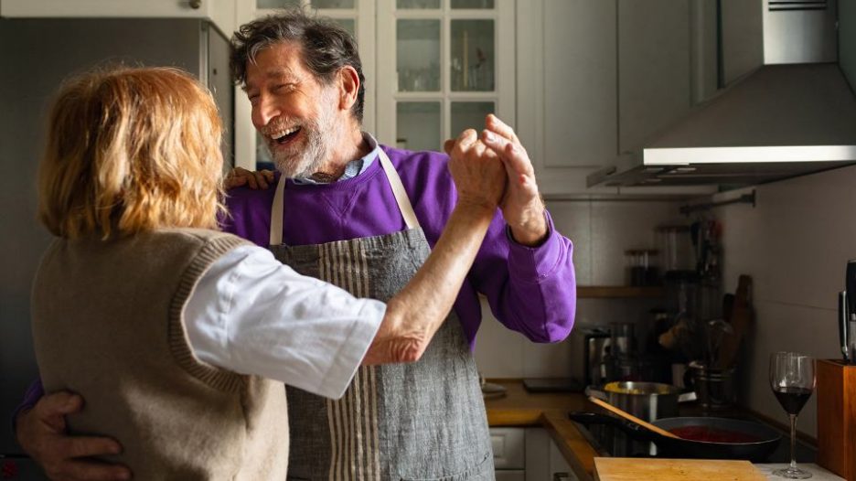 older couple laughing and dancing in kitchen