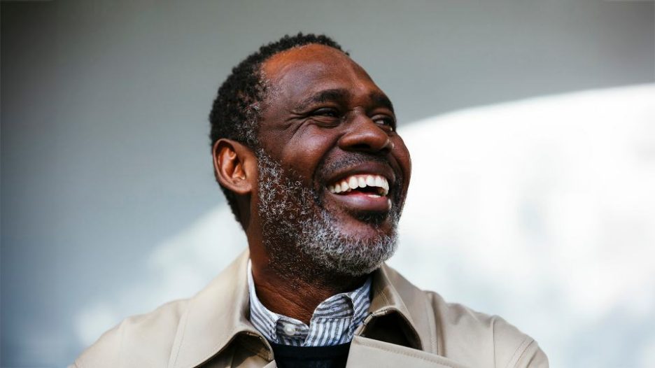 mature male in formal clothes smiling and looking at camera while standing outdoors