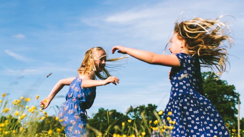 2 little girls dancing in a meadow