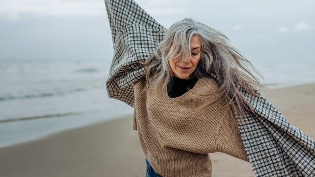 senior woman dancing on a winters day on the beach