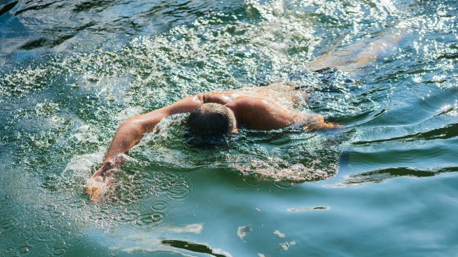 man swimming face down in lake